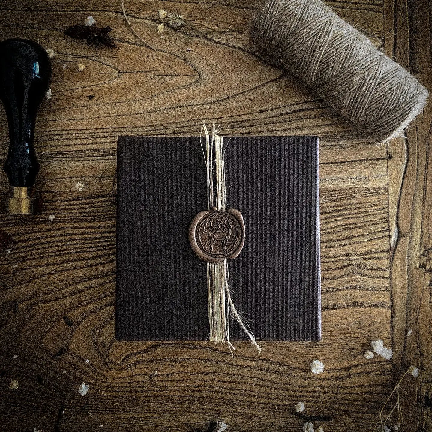 A dark sealed Spiramirabilis box with wax stamp and twine on a wooden table